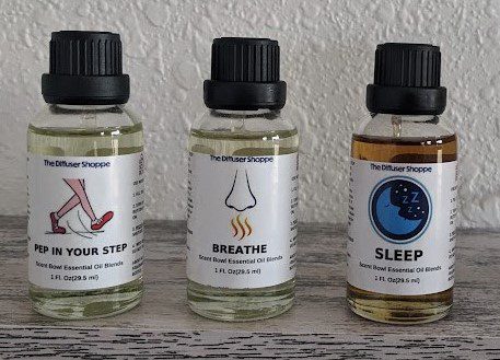 Three bottles of oils are sitting on a shelf.